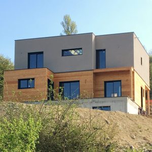 Maison ossature bois avec bardage Mélèze saturé et enduit, couverture membrane d&rsquo;étanchéité, menuiseries aluminium à Abrest