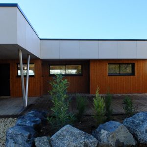 Maison ossature bois sur pilotis bardage saturé Teck, couverture membrane d&rsquo;étanchéité, menuiseries aluminium à Abrest